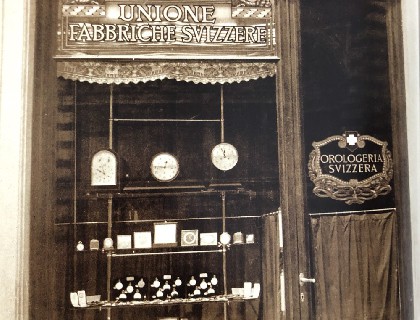 1930年代所拍照片上的圣乔凡尼广炀瑞士钟表店，当时该店经营许多顶级手表品牌。看起来，其大门及表店橱窗几乎全无改变，而玻璃门镜上的古老文字商标也依旧保留。