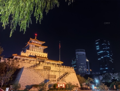 济南市地标建筑“解放阁”庄严而肃穆，红星耸立在阁楼之顶，阁楼前红旗高挂，街道行人川流不息。